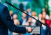 Speaker at podium with microphone addressing crowd