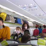 Passengers with masks boarding an airplane cabin