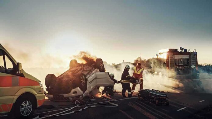 shutterstock_1721662801 Firefighters at overturned car crash scene at sunset