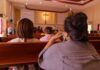 Ecuador Priest Dies in Sudden Church Tragedy people seated in church pews facing a cross