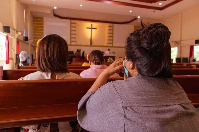 shutterstock_1773600770-1 people seated in church pews facing a cross
