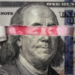 portrait on banknote with torn strip revealing red eyes