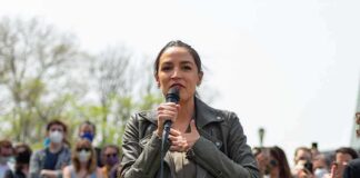 woman speaking into a microphone at an outdoor rally