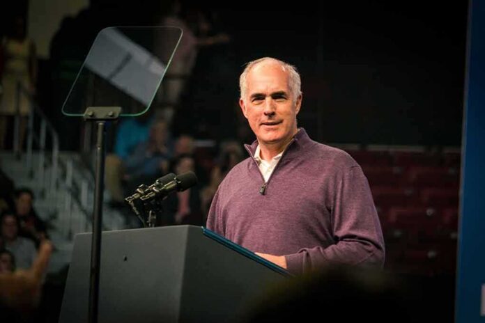 shutterstock_2231122653 Bob P. Casey, Jr. speaking at a podium with microphones and teleprompter