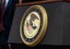 Feds Asked Former Mob Boss to Decode Comey Post Department of Justice seal on a podium