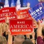 Crowd holding red and blue campaign signs at a political rally
